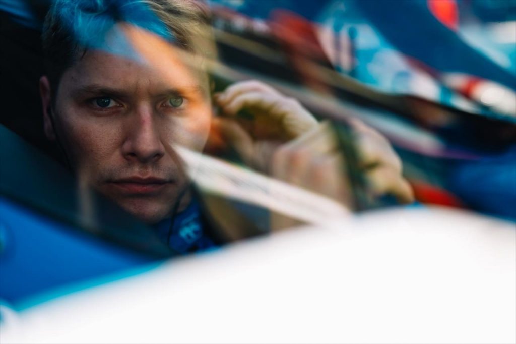 Josef Newgarden in the cockpit of his car, staring into the camera.